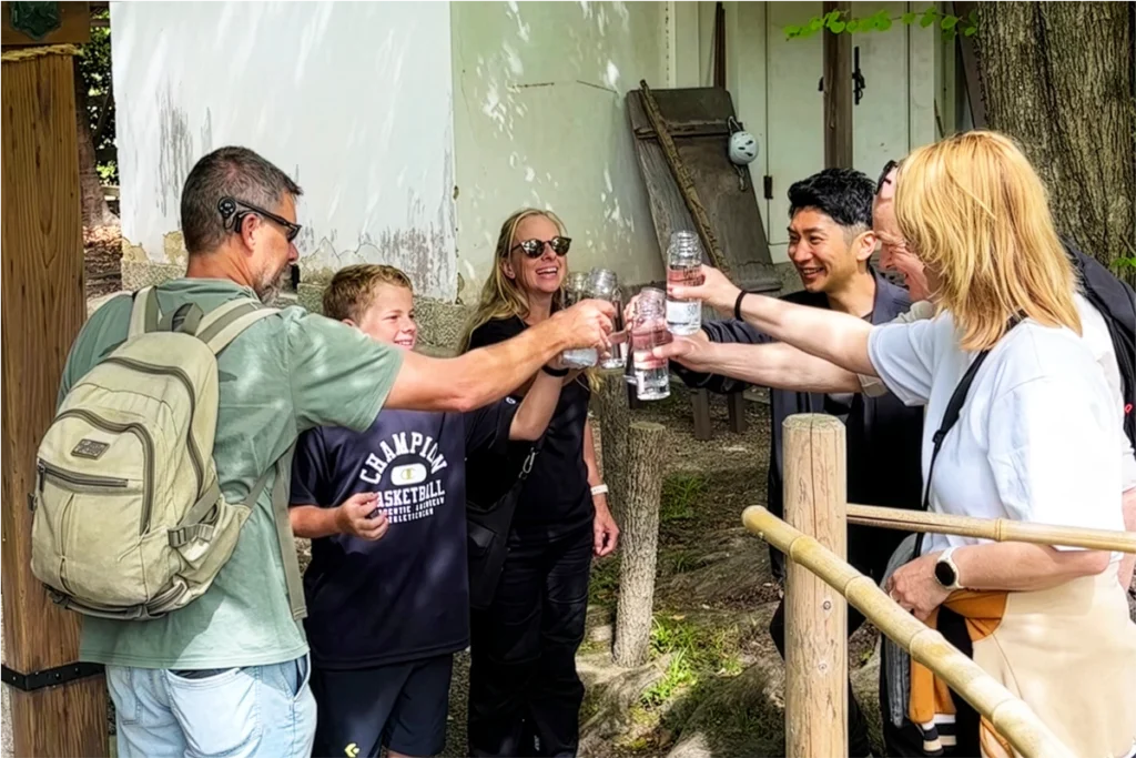 Guests toasting with water bottles after collecting spring water at Nashinoki Shrine during the SunnyCycle Kyoto e-bike tour